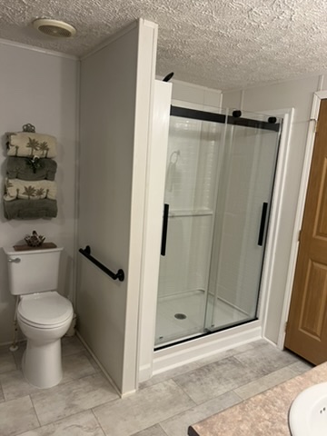 Remodeled bathroom showing the new toilet and shower with glass doors.