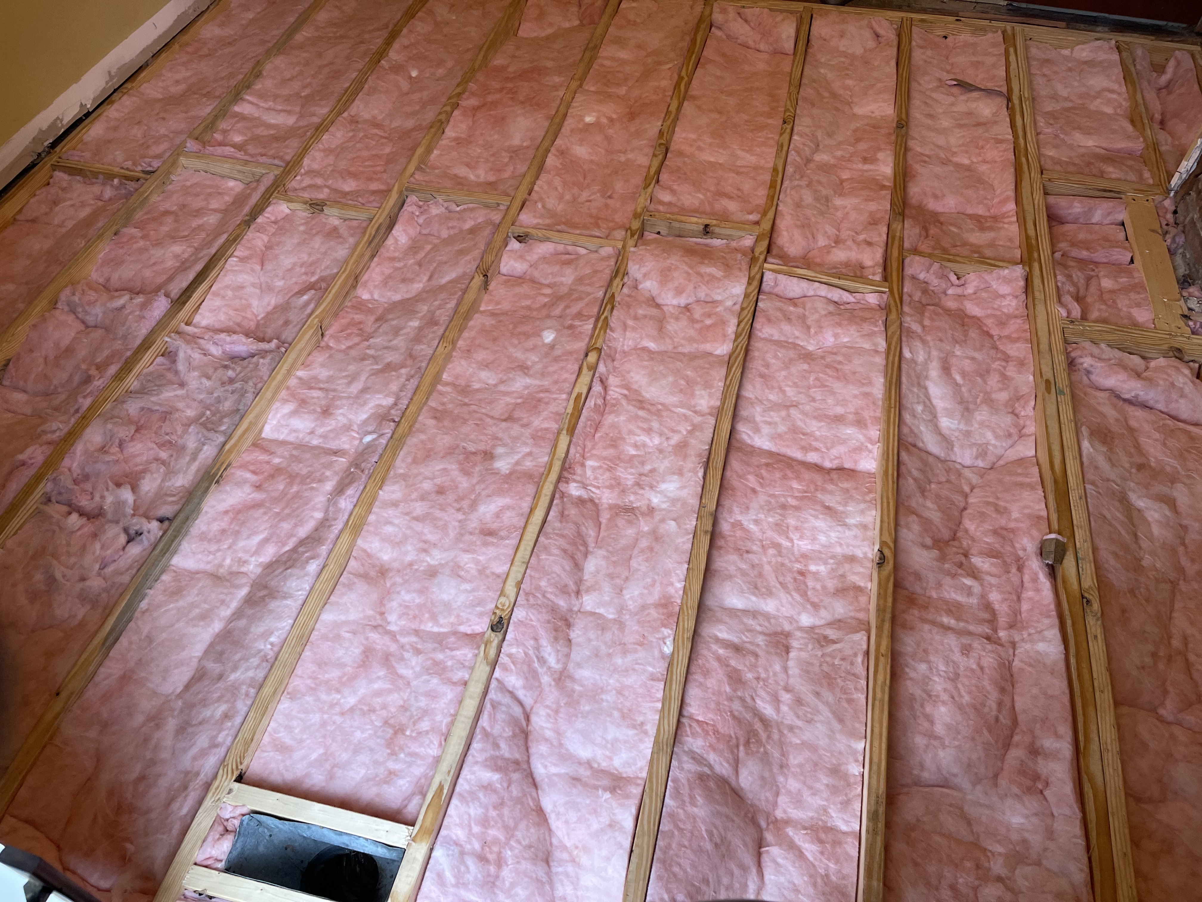 New floor joists and insulation installed before new subfloor and flooring.